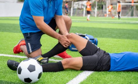 Footballer wearing a blue shirt, black pants injured in the lawn during the race.